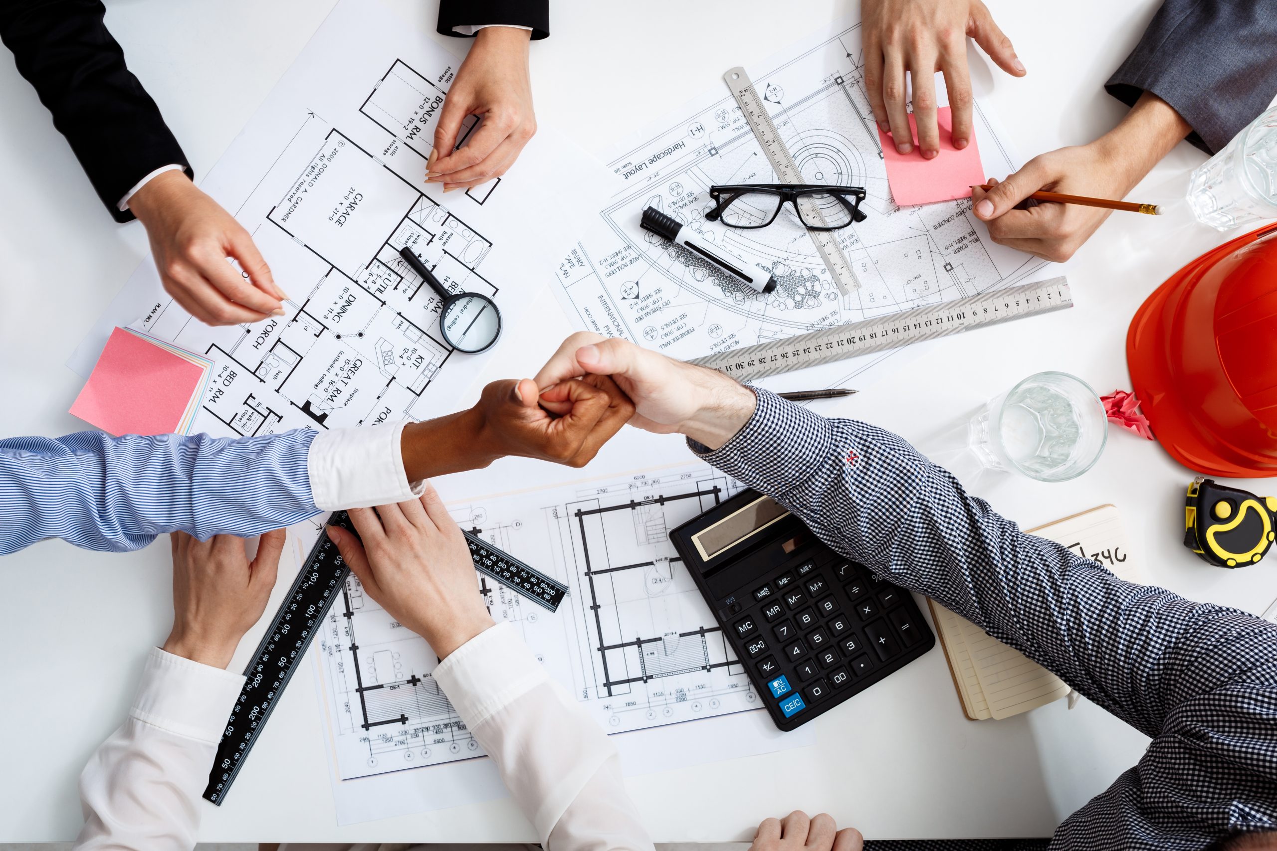 Picture of businessmen’s hands on white table with documents and drafts